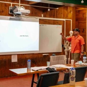 Man presents information on a whiteboard to an audience.